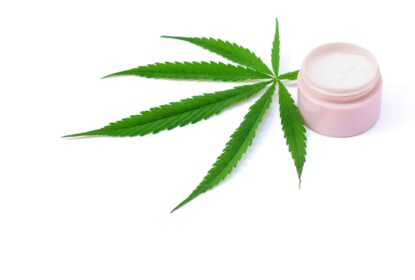 cannabis leaf next to with jar of topical lotion